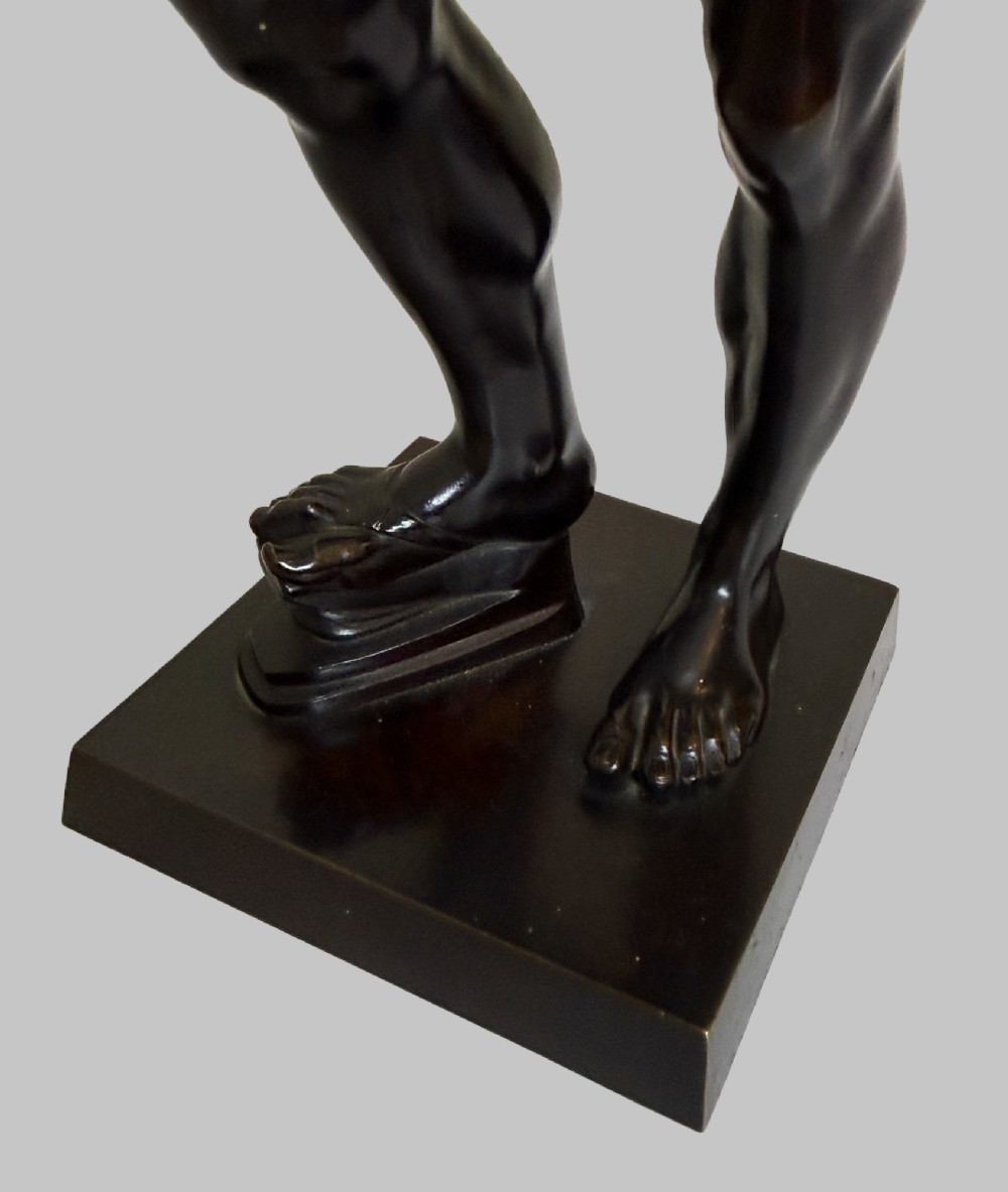 A dark patinated bronze statue depicting a nude classical dancing faun holding cymbals, mounted on a square black base. View VII