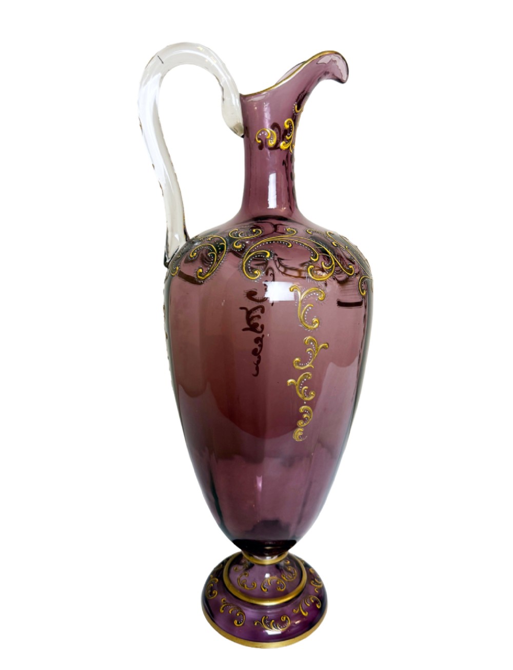A 19th-century blown violet glass ewer featuring a clear glass handle, slender neck, circular base, and hand-painted gilt scroll patterns.