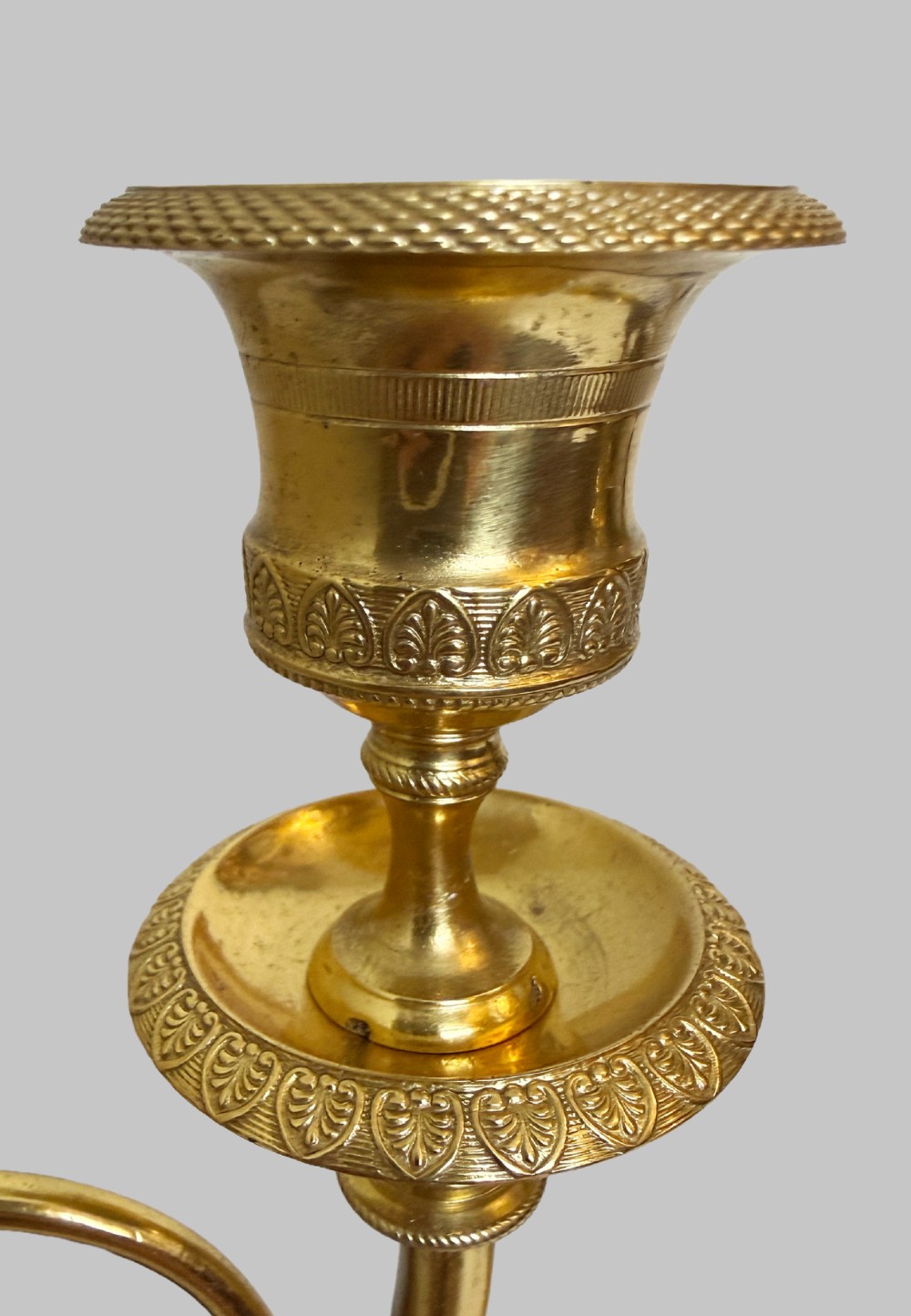 A pair of 19th-century gilt and patinated bronze candlesticks featuring dark cherubs seated on cylindrical pedestals with gilt winged lion motifs, holding gold-toned horn sconces. View VII