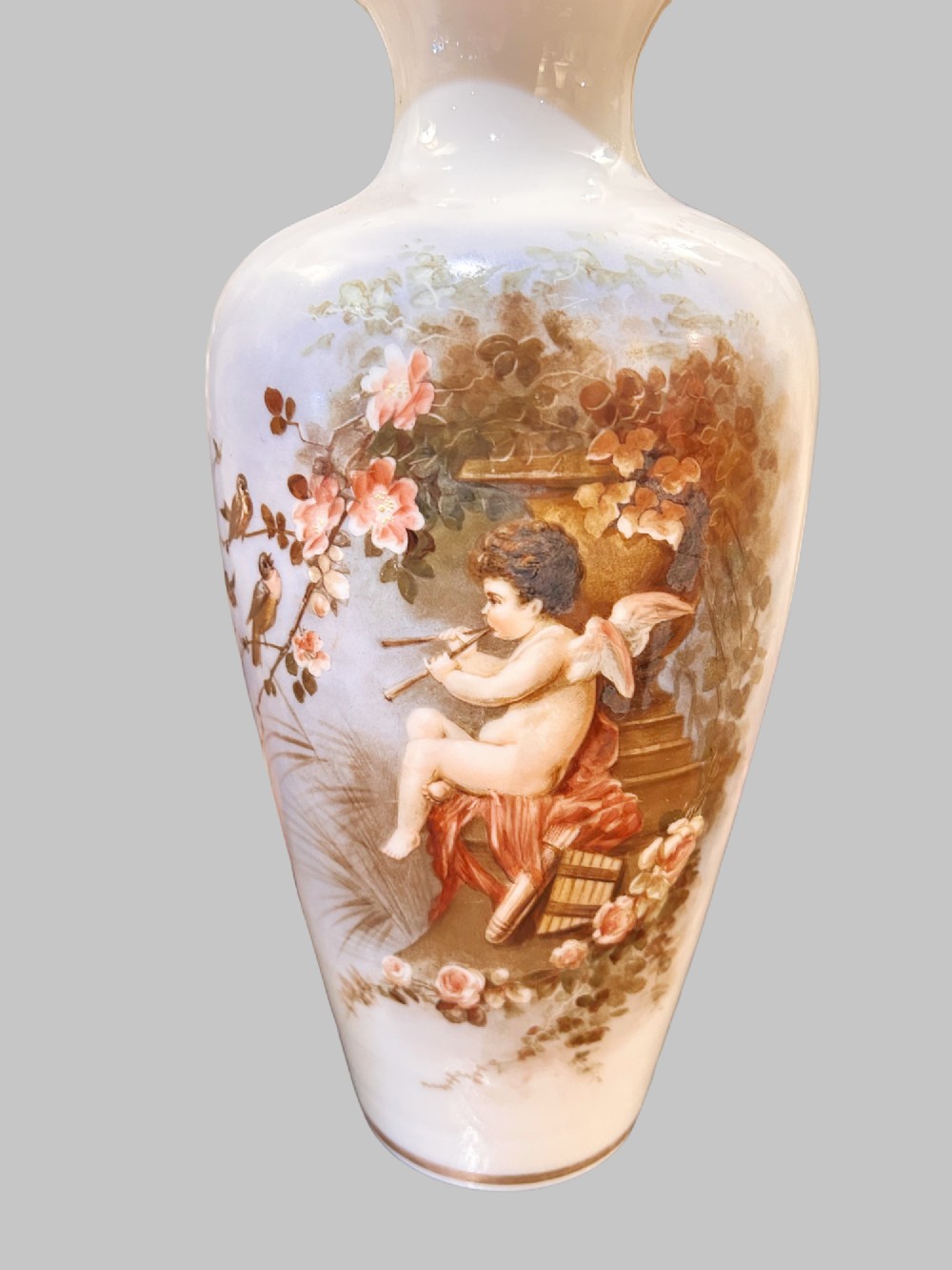 A pair of white porcelain baluster vases decorated with painted scenes of cherubs playing musical instruments in a garden, finished with gilt rims. View III