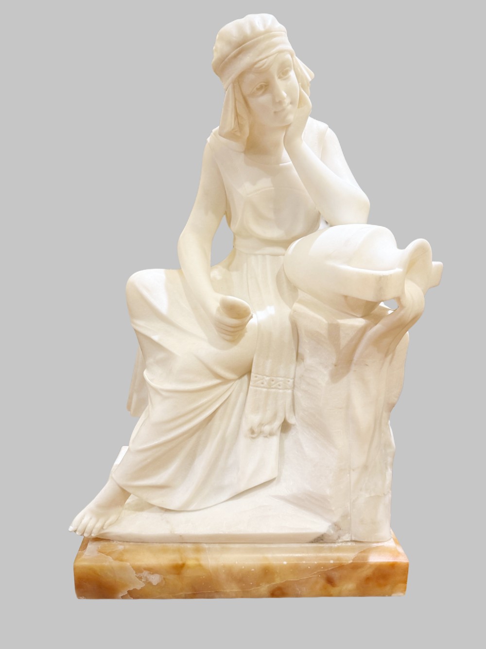 A carved white alabaster sculpture depicting a seated young maiden resting her chin on her hand beside a pitcher, mounted on a rectangular honey-coloured marble base. View III