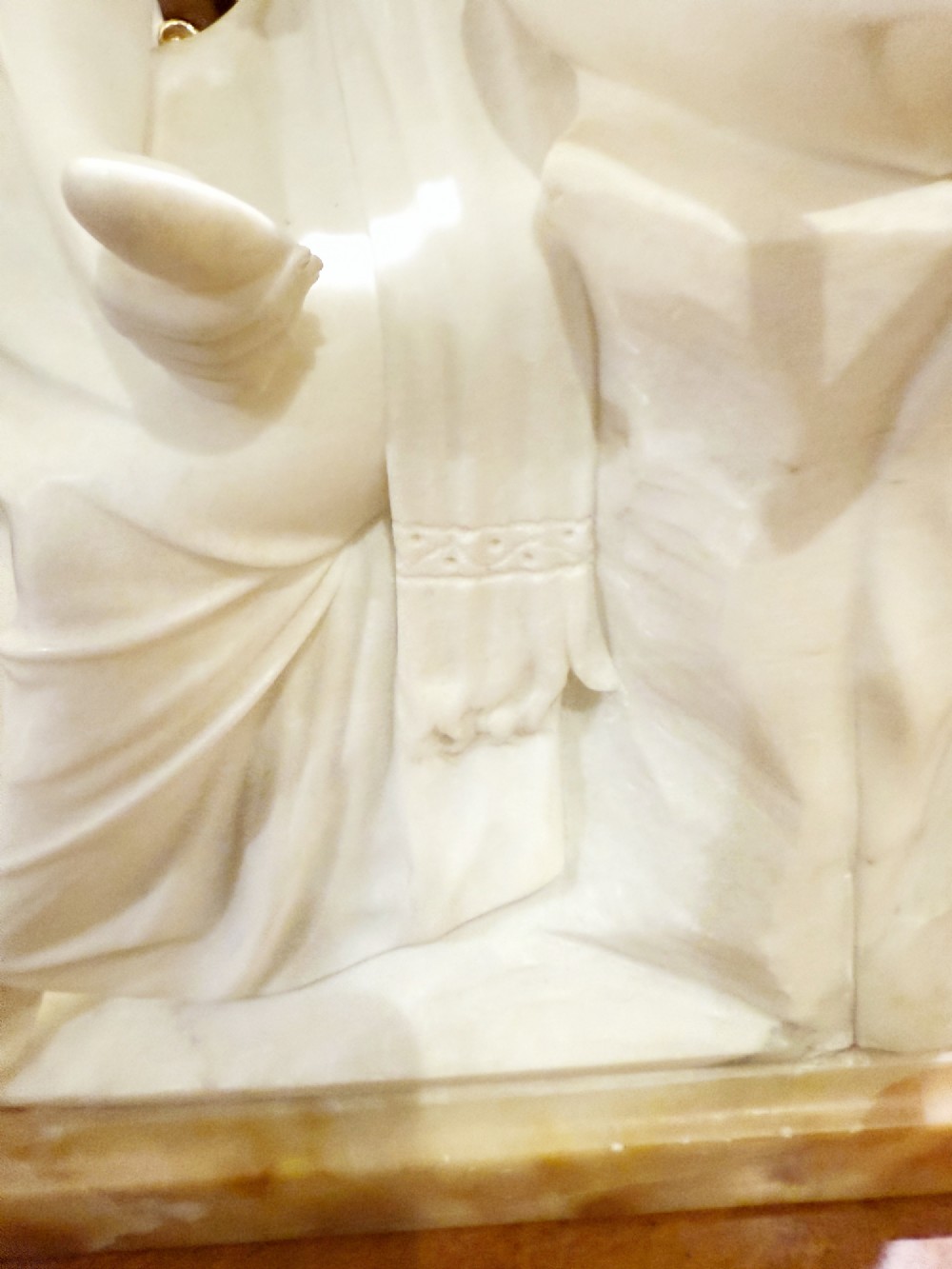 A carved white alabaster sculpture depicting a seated young maiden resting her chin on her hand beside a pitcher, mounted on a rectangular honey-coloured marble base. View V