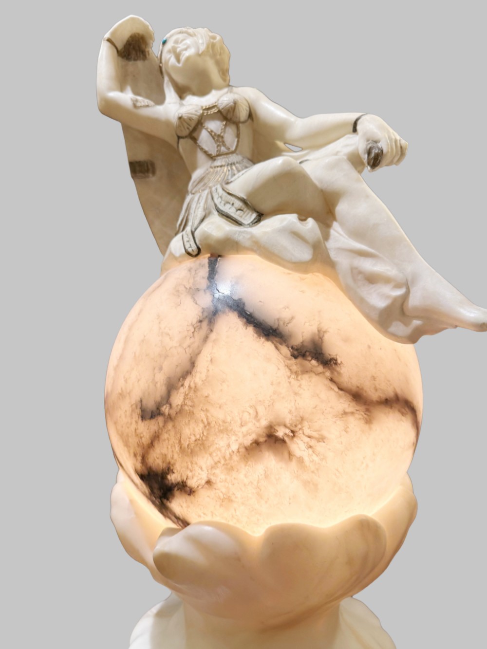 An Art Deco carved alabaster sculpture featuring a female dancer posed atop an illuminated marble orb resting on a shell-shaped pedestal base. View II