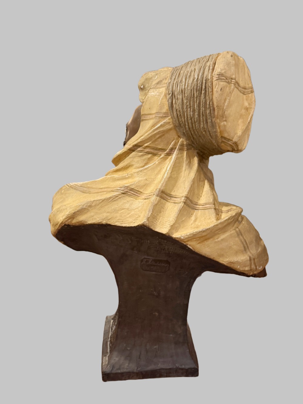 A cold-painted polychrome terracotta bust of a young North African man wearing a draped yellow headscarf mounted on a dark pedestal base. View IV