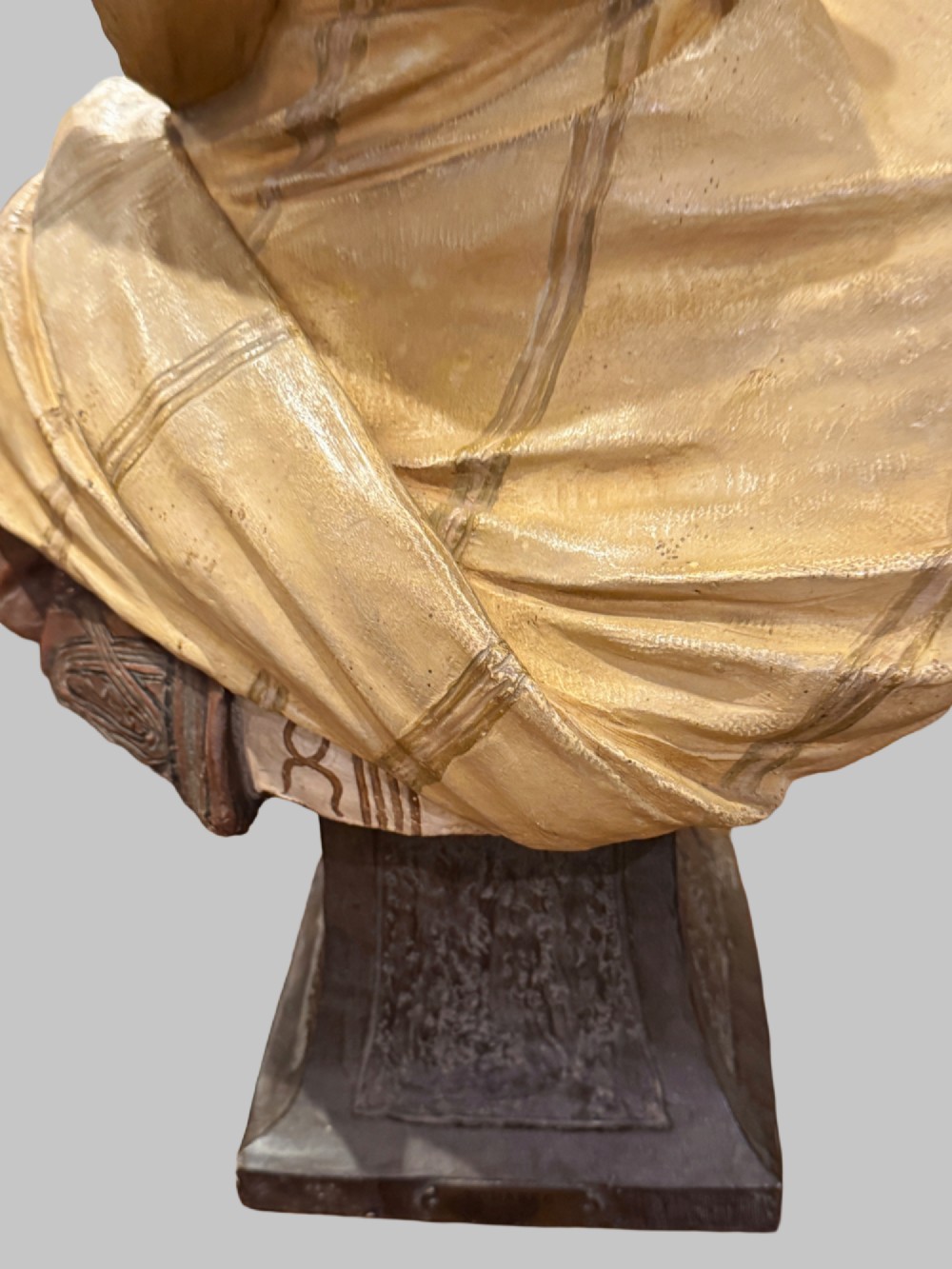 A cold-painted polychrome terracotta bust of a young North African man wearing a draped yellow headscarf mounted on a dark pedestal base. View IX