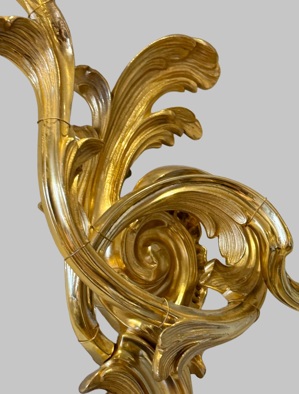 A pair of gilt bronze two-light wall sconces featuring elaborate Rococo scrolling acanthus leaf metalwork and cream candle sleeves. View II