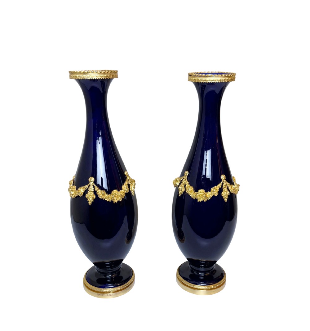 A pair of 19th-century deep cobalt blue porcelain vases decorated with gilt bronze floral garland swags and gilded rim bases.