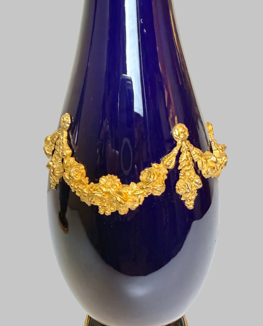 A pair of 19th-century deep cobalt blue porcelain vases decorated with gilt bronze floral garland swags and gilded rim bases. View II