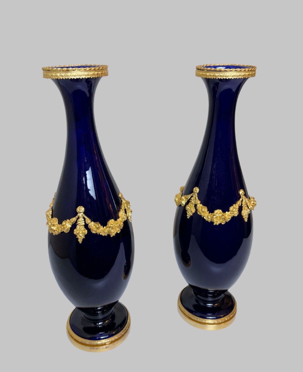A pair of 19th-century deep cobalt blue porcelain vases decorated with gilt bronze floral garland swags and gilded rim bases. View VI
