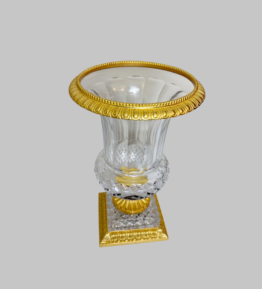 A clear cut-crystal urn-shaped vase featuring fluted body detailing, diamond-pattern cutting, and a gilt bronze rim and square pedestal base. View IV