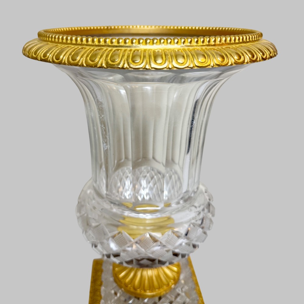 A clear cut-crystal urn-shaped vase featuring fluted body detailing, diamond-pattern cutting, and a gilt bronze rim and square pedestal base. View VI