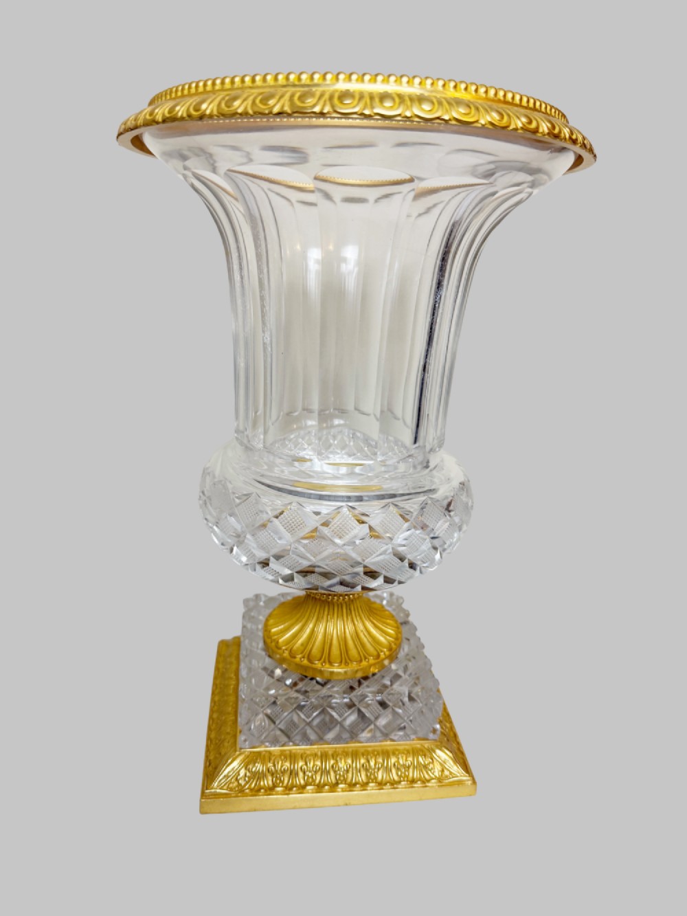 A clear cut-crystal urn-shaped vase featuring fluted body detailing, diamond-pattern cutting, and a gilt bronze rim and square pedestal base. View VII