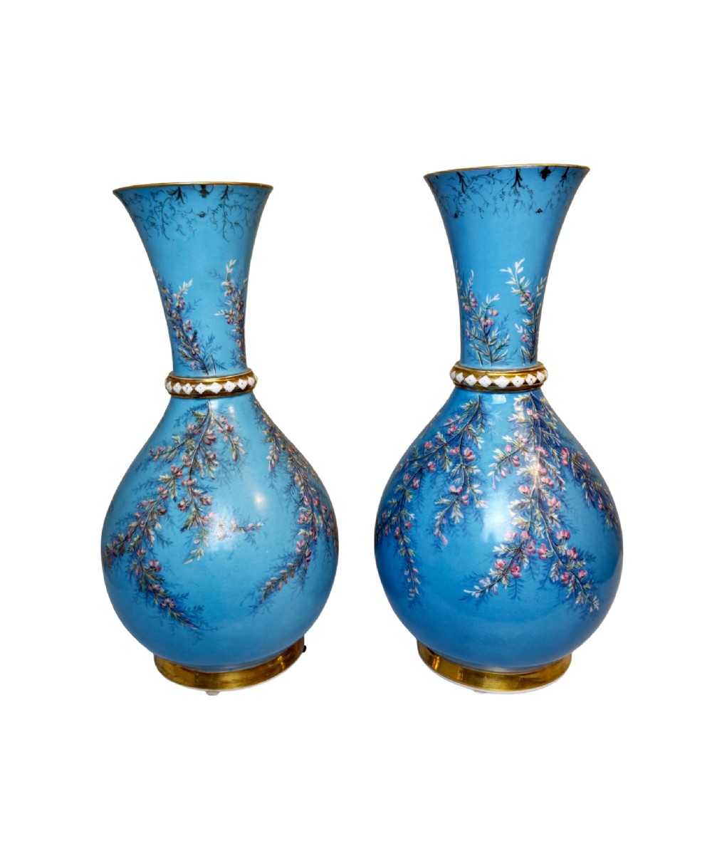 A pair of tall sky blue porcelain vases with bulbous bases, hand-painted floral branch motifs, and gilded rims and pedestals.