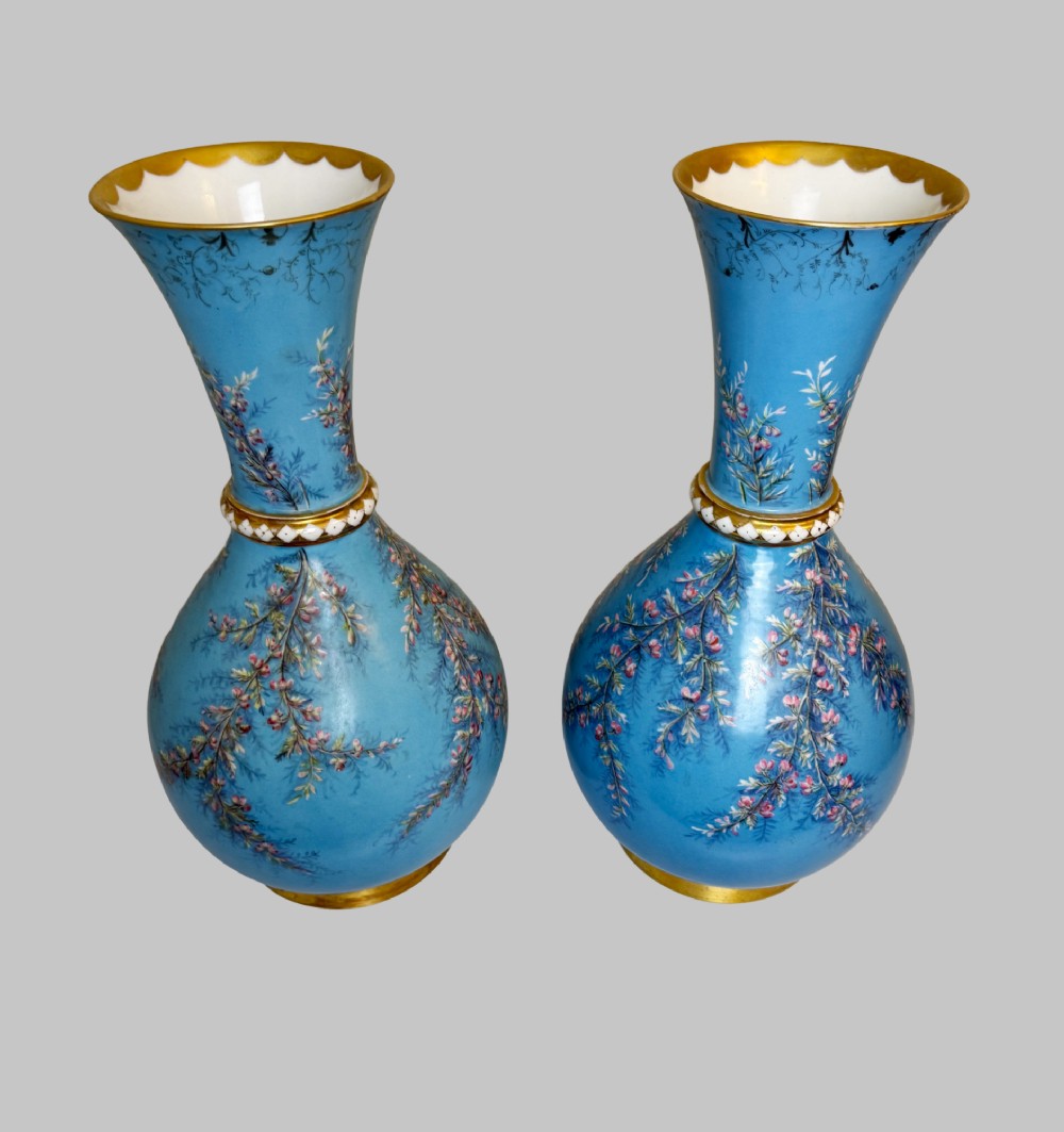 A pair of tall sky blue porcelain vases with bulbous bases, hand-painted floral branch motifs, and gilded rims and pedestals. View VII