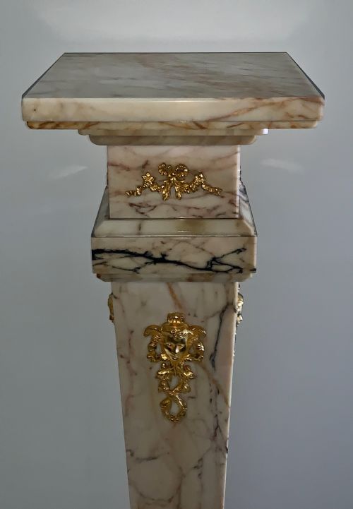 fig 2. A tapered beige veined marble pedestal stand featuring ornate gilt bronze mounts and a square swivel top set upon a stepped base.
