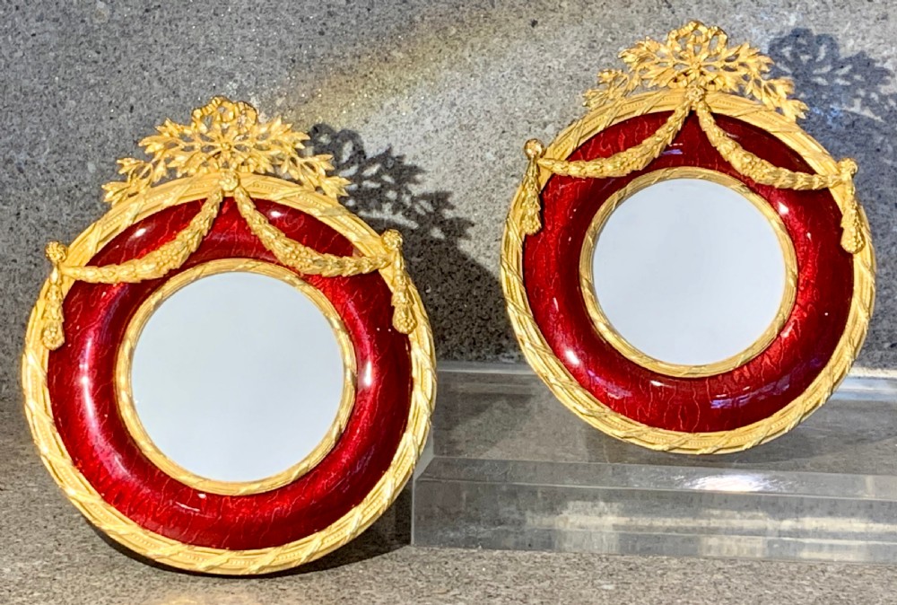 A pair of circular French Napoleon III gilt bronze and red enamel picture frames featuring decorative bow crests and floral garland detailing. View II