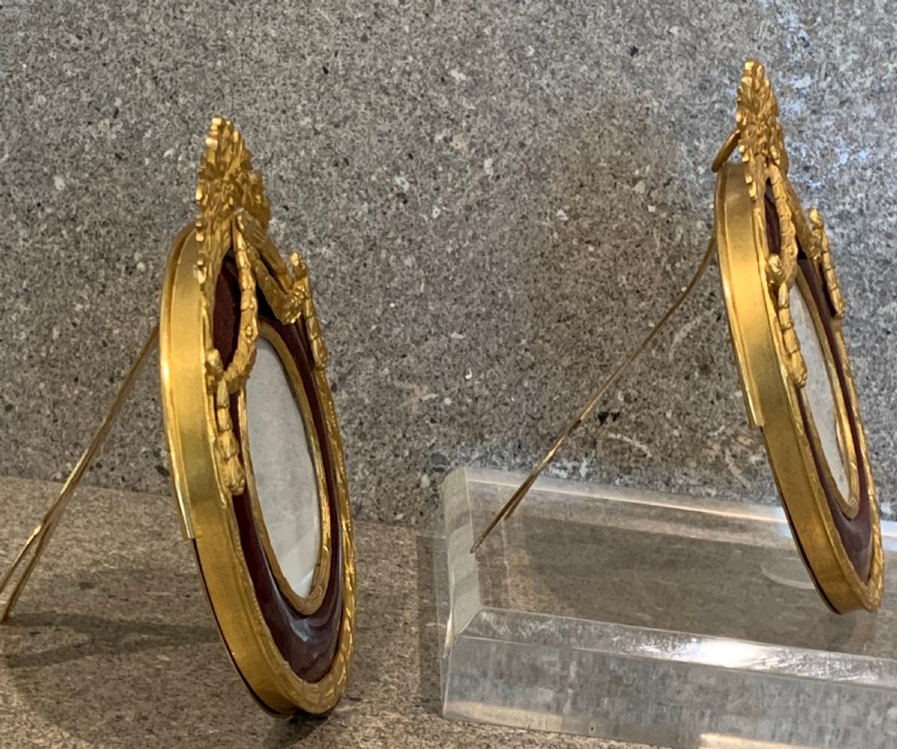 A pair of circular French Napoleon III gilt bronze and red enamel picture frames featuring decorative bow crests and floral garland detailing. View III