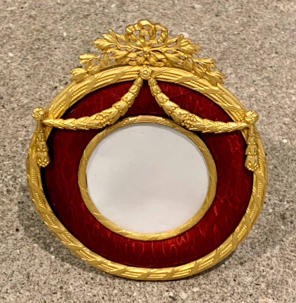 A pair of circular French Napoleon III gilt bronze and red enamel picture frames featuring decorative bow crests and floral garland detailing. View VII