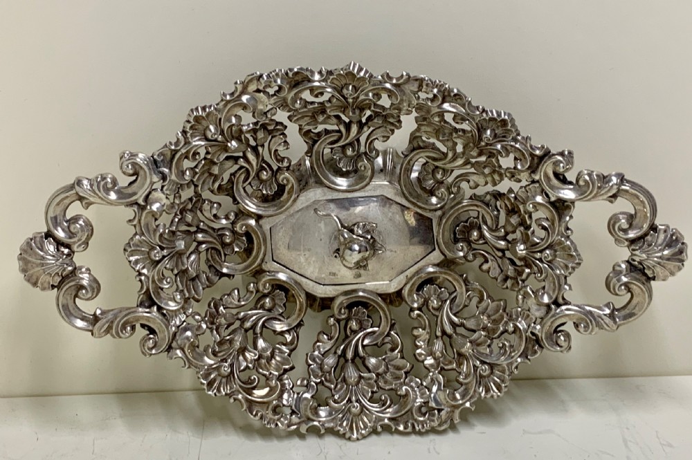 An oval antique silver basket featuring intricate openwork scrollwork, foliage motifs, and two integrated side handles. View II
