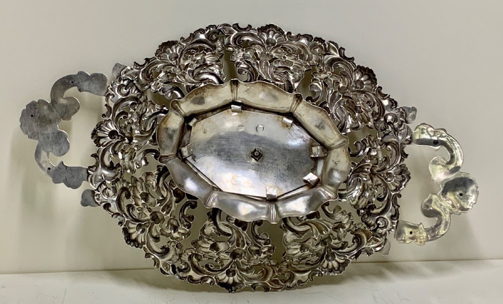 An oval antique silver basket featuring intricate openwork scrollwork, foliage motifs, and two integrated side handles. View VIII