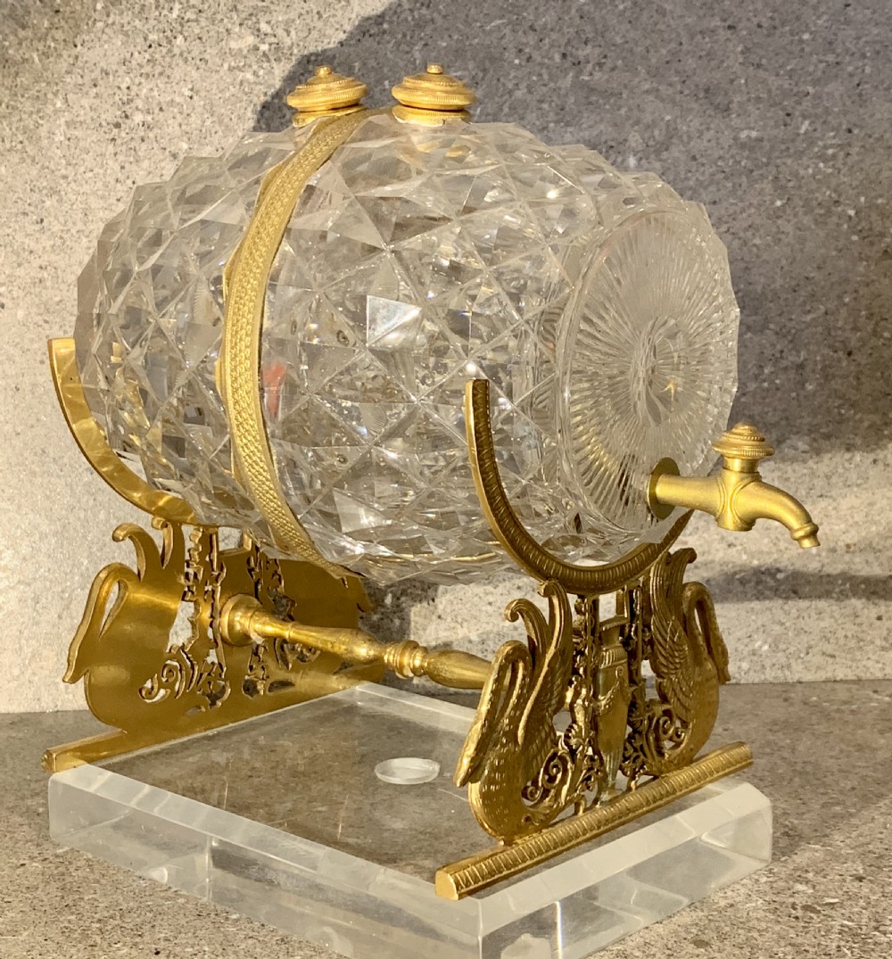 A French Charles X cut crystal glass barrel with gilt bronze swan-form mounts and an integrated tap set on a clear glass base. View II