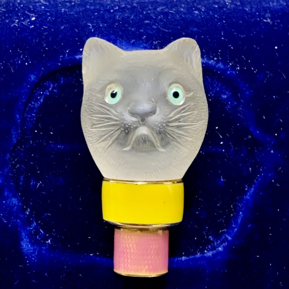 A carved frosted rock crystal cat head featuring green eyes, mounted atop an 18k gold collar with yellow and pink guilloche enamel.
