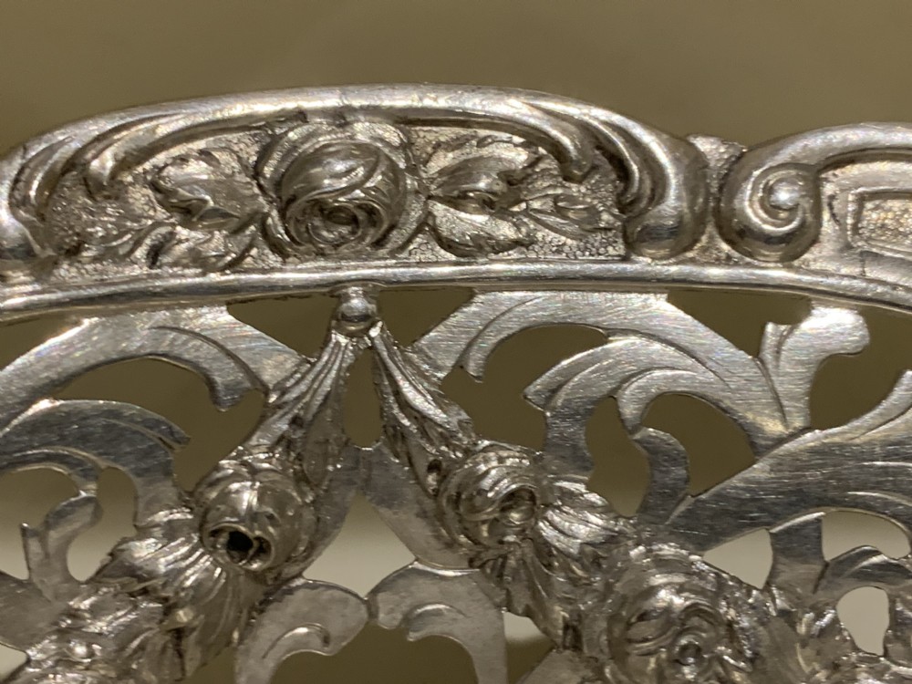 A circular antique solid silver bread basket featuring intricate hand-pierced fretwork, repousse floral swags, and a contoured scalloped rim. View XIV