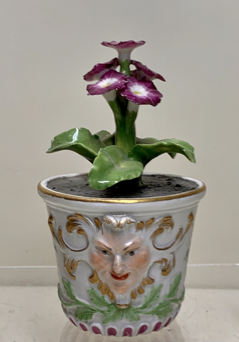 An 18th-century Meissen porcelain botanical sculpture featuring purple flowers and green leaves inside a white potted tub decorated with a mascaron mask and gold scrollwork. View III