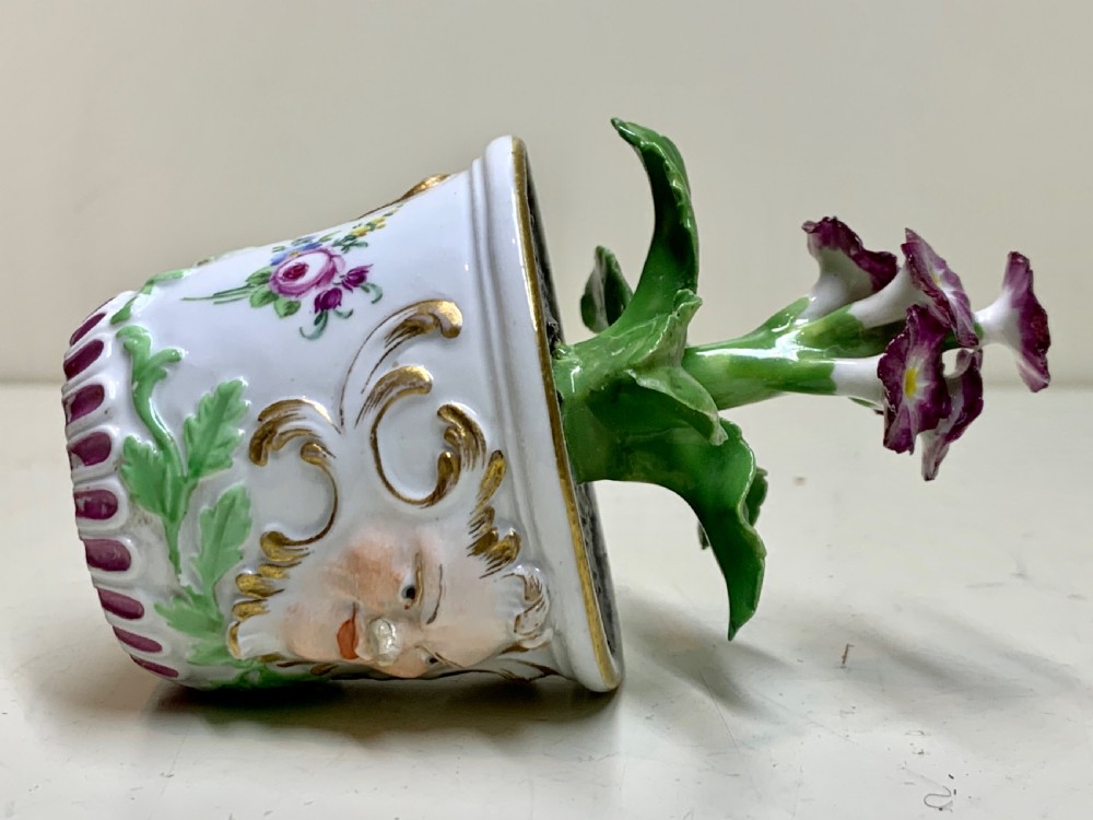 An 18th-century Meissen porcelain botanical sculpture featuring purple flowers and green leaves inside a white potted tub decorated with a mascaron mask and gold scrollwork. View VII