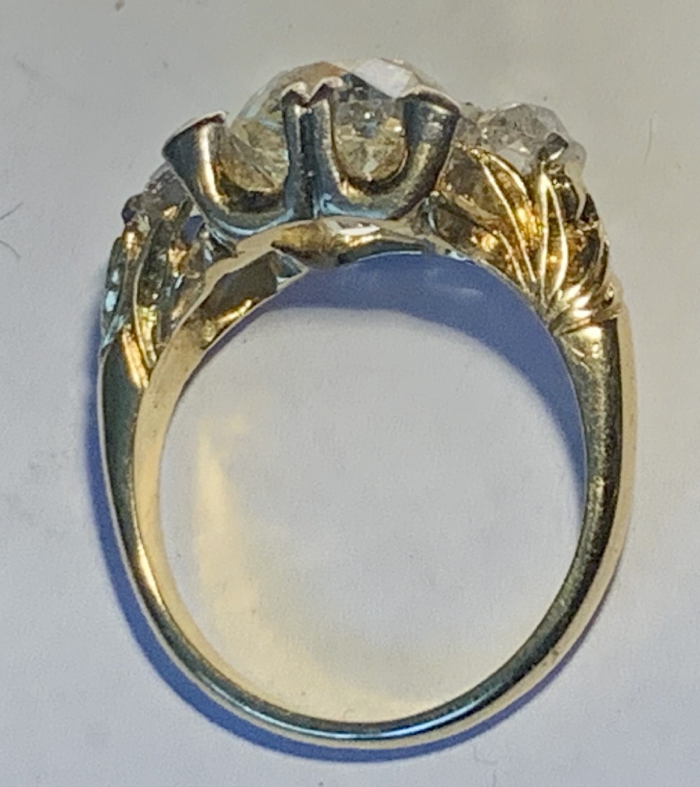 A Victorian 18ct yellow gold ring set with a central old European cut diamond flanked by smaller accent diamonds. View X