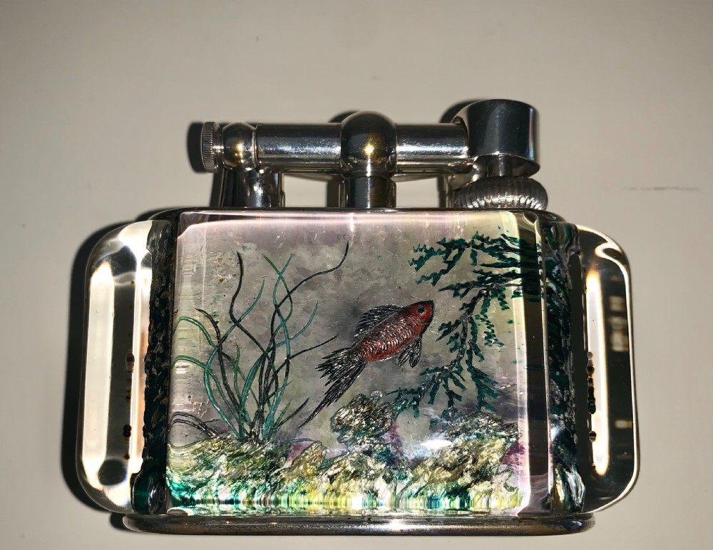 A mid-century Dunhill Aquarium table lighter featuring transparent acrylic panels reverse-carved with angelfish and aquatic plants beneath a silver-toned lift-arm mechanism. View VII