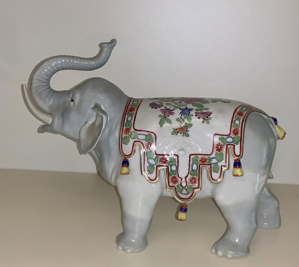 A large Dresden porcelain elephant figure painted in grey with a raised trunk and an ornate, colourful hand-painted saddle blanket. View III