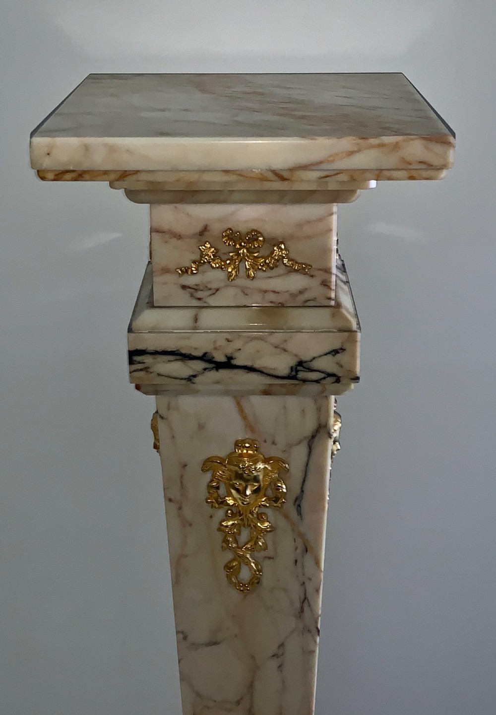 A tapered beige veined marble pedestal stand featuring ornate gilt bronze mounts and a square swivel top set upon a stepped base. View III