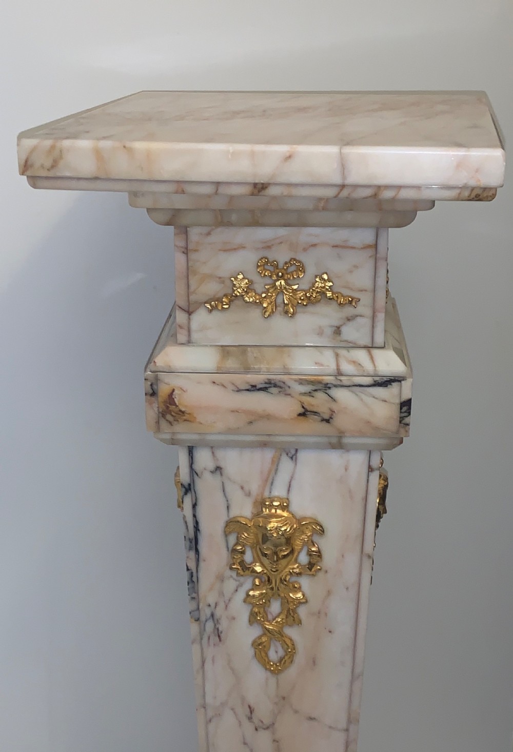 A tapered beige veined marble pedestal stand featuring ornate gilt bronze mounts and a square swivel top set upon a stepped base. View X