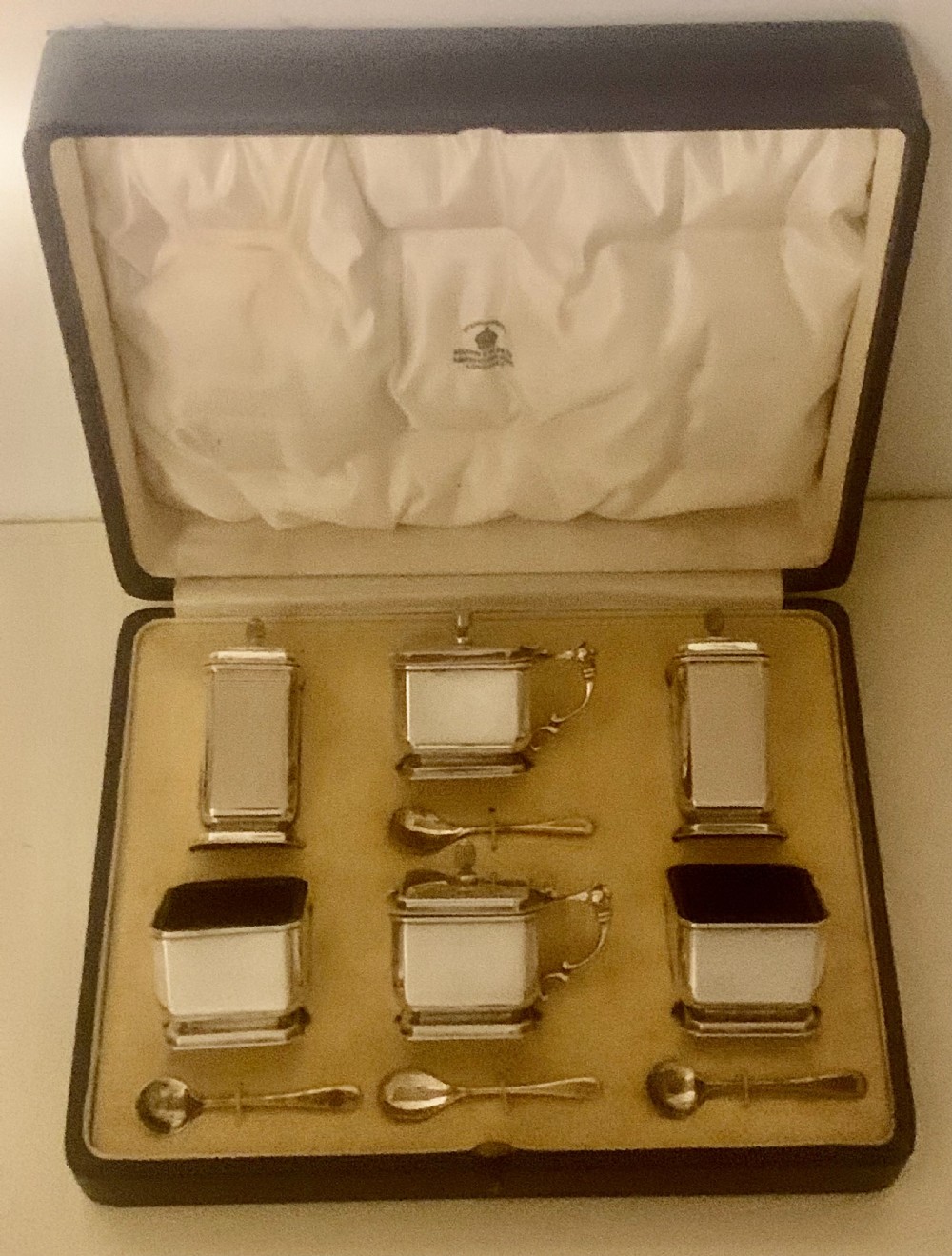 A six-piece Art Deco silver condiment set with matching spoons presented inside a fitted blue presentation box.