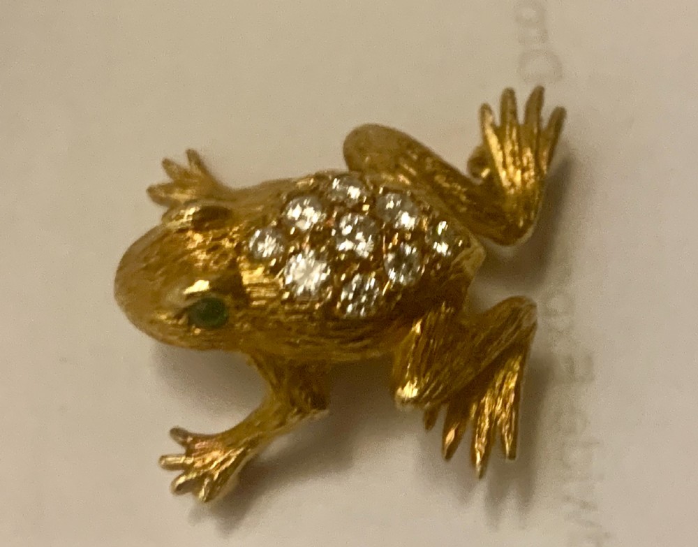 A textured gold frog brooch set with diamonds along its back and green gemstone eyes. View V