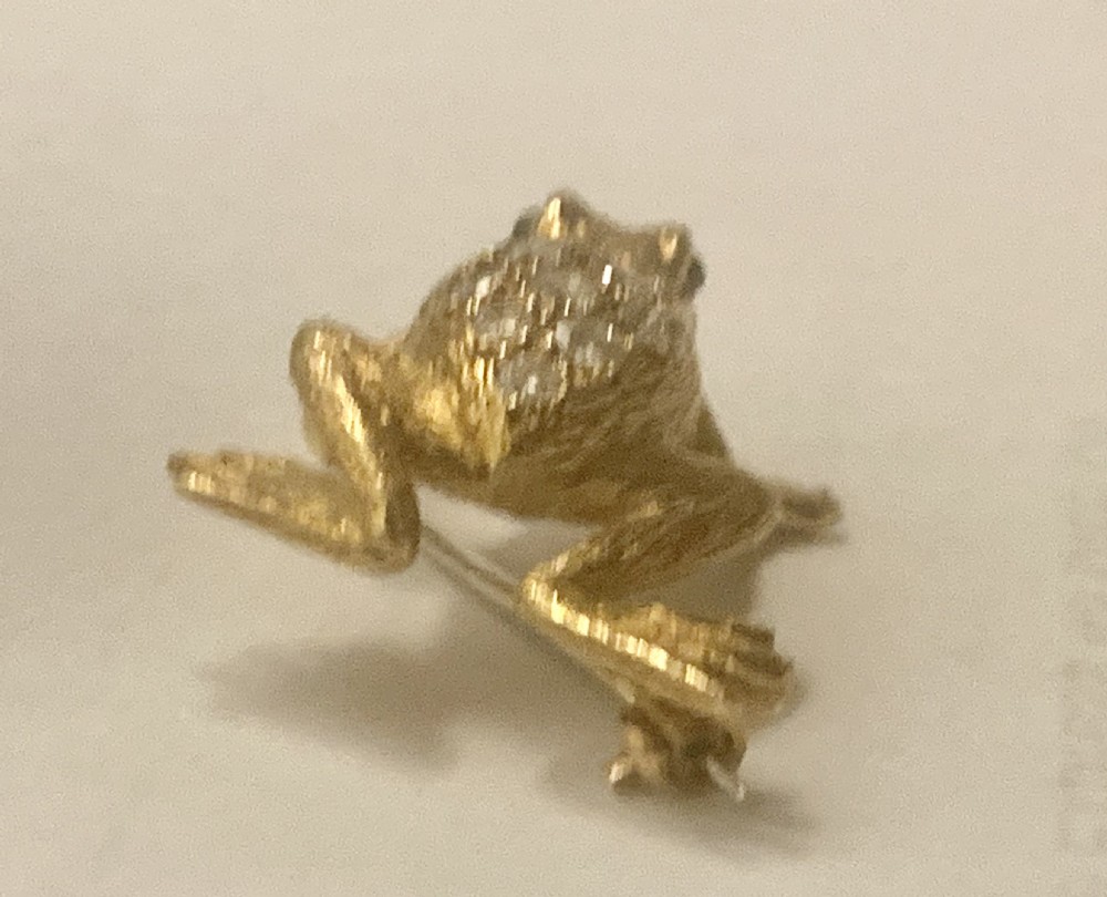 A textured gold frog brooch set with diamonds along its back and green gemstone eyes. View VII