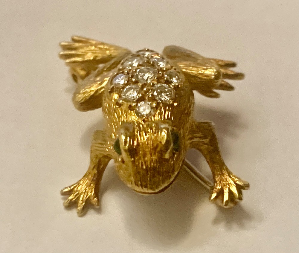 A textured gold frog brooch set with diamonds along its back and green gemstone eyes. View VIII