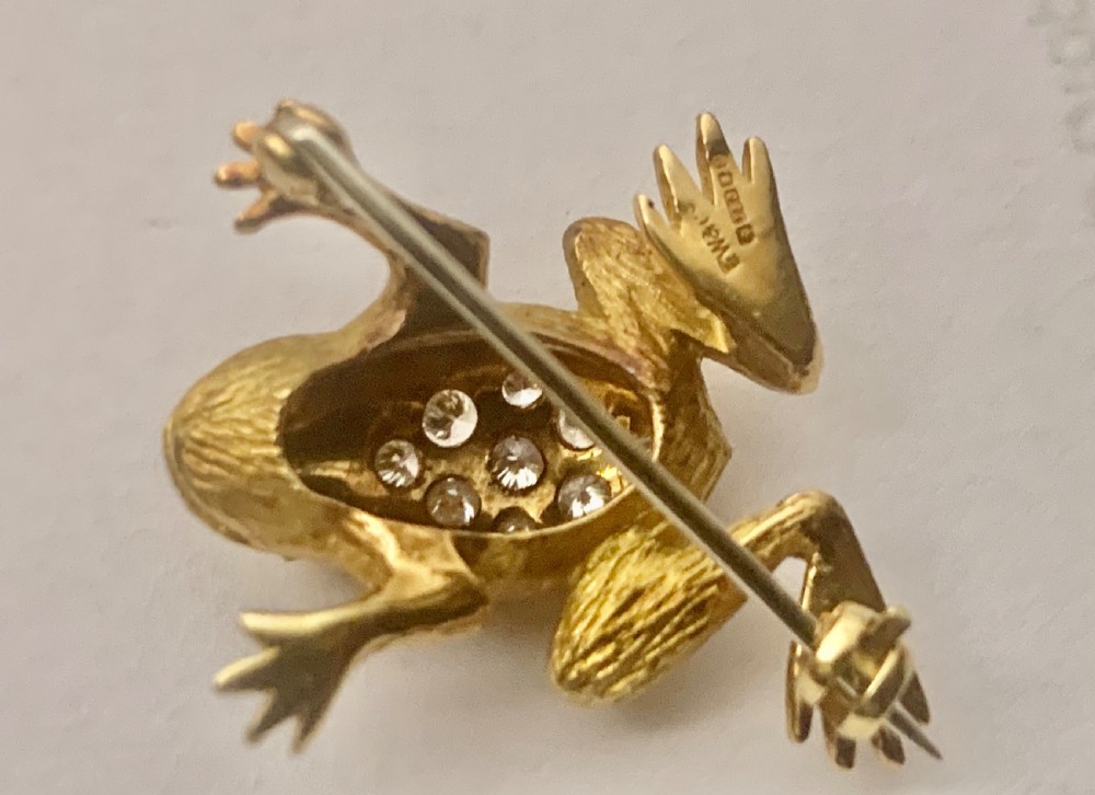 A textured gold frog brooch set with diamonds along its back and green gemstone eyes. View IX