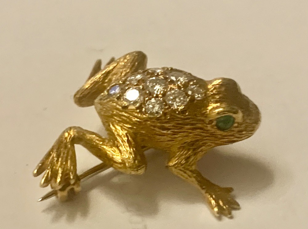 A textured gold frog brooch set with diamonds along its back and green gemstone eyes. View X