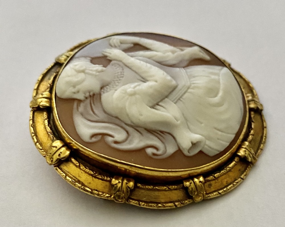 An antique circular brooch featuring a hand-carved shell cameo of a classical female figure set in a textured 15ct yellow gold frame. View IV