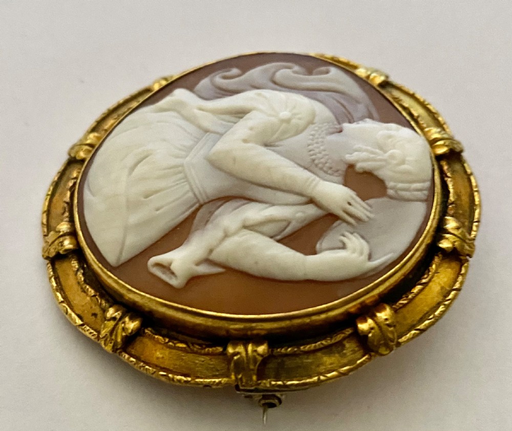 An antique circular brooch featuring a hand-carved shell cameo of a classical female figure set in a textured 15ct yellow gold frame. View V