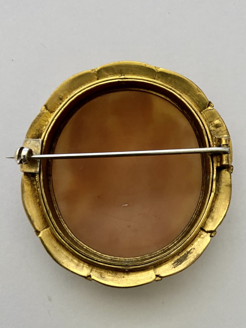 An antique circular brooch featuring a hand-carved shell cameo of a classical female figure set in a textured 15ct yellow gold frame. View IX