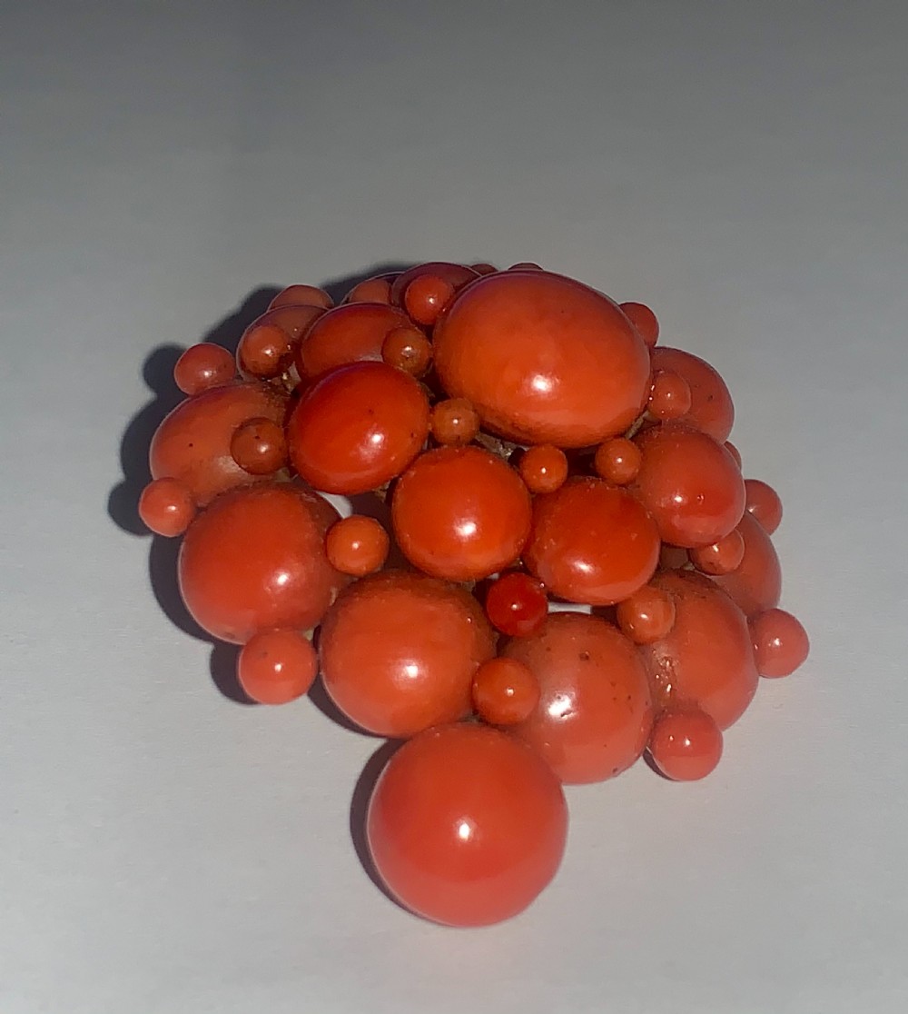 An antique Victorian domed cluster brooch composed of polished salmon-pink coral beads set in a multi-tiered arrangement. View III