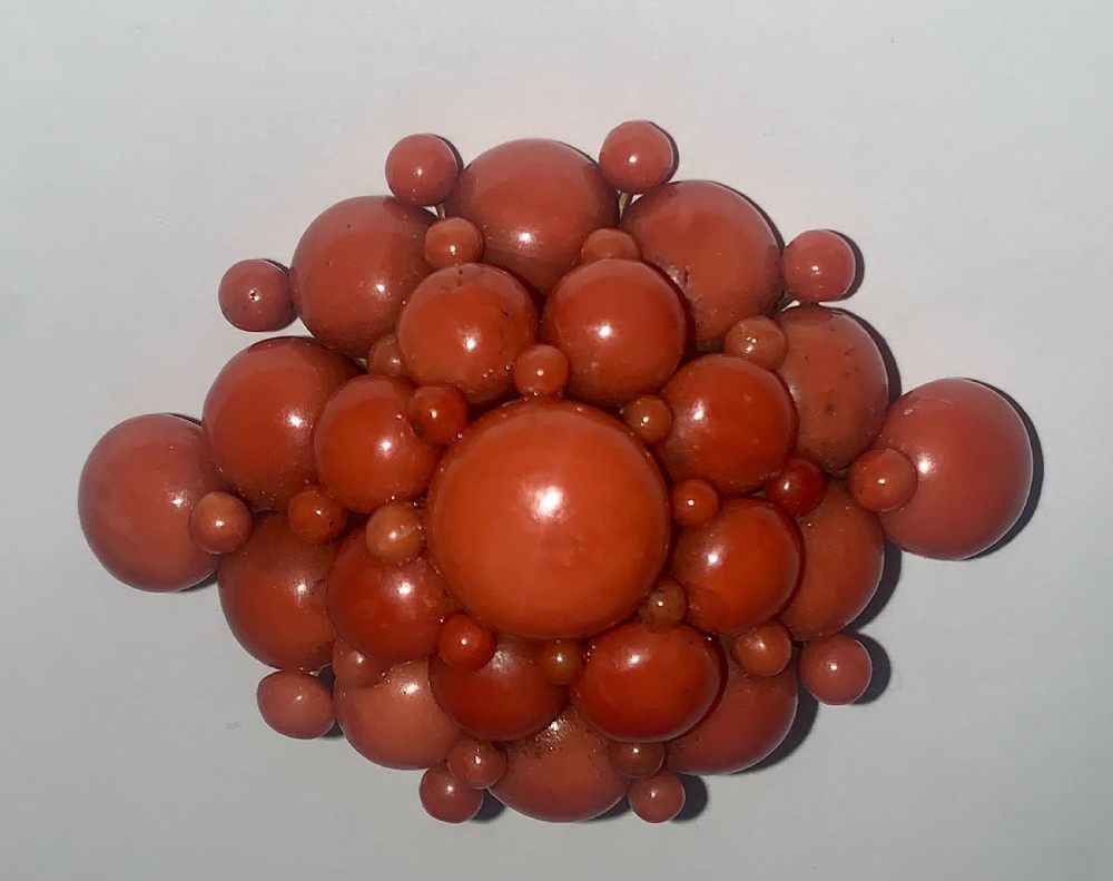 An antique Victorian domed cluster brooch composed of polished salmon-pink coral beads set in a multi-tiered arrangement. View IV