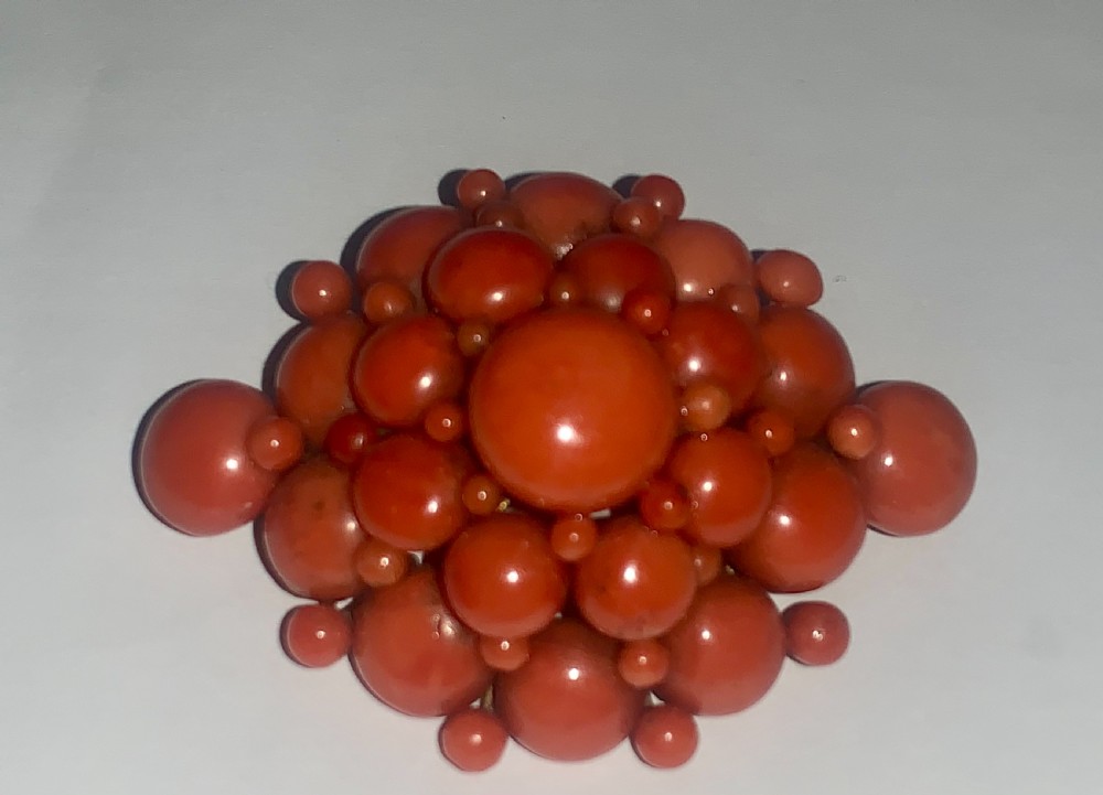 An antique Victorian domed cluster brooch composed of polished salmon-pink coral beads set in a multi-tiered arrangement. View II