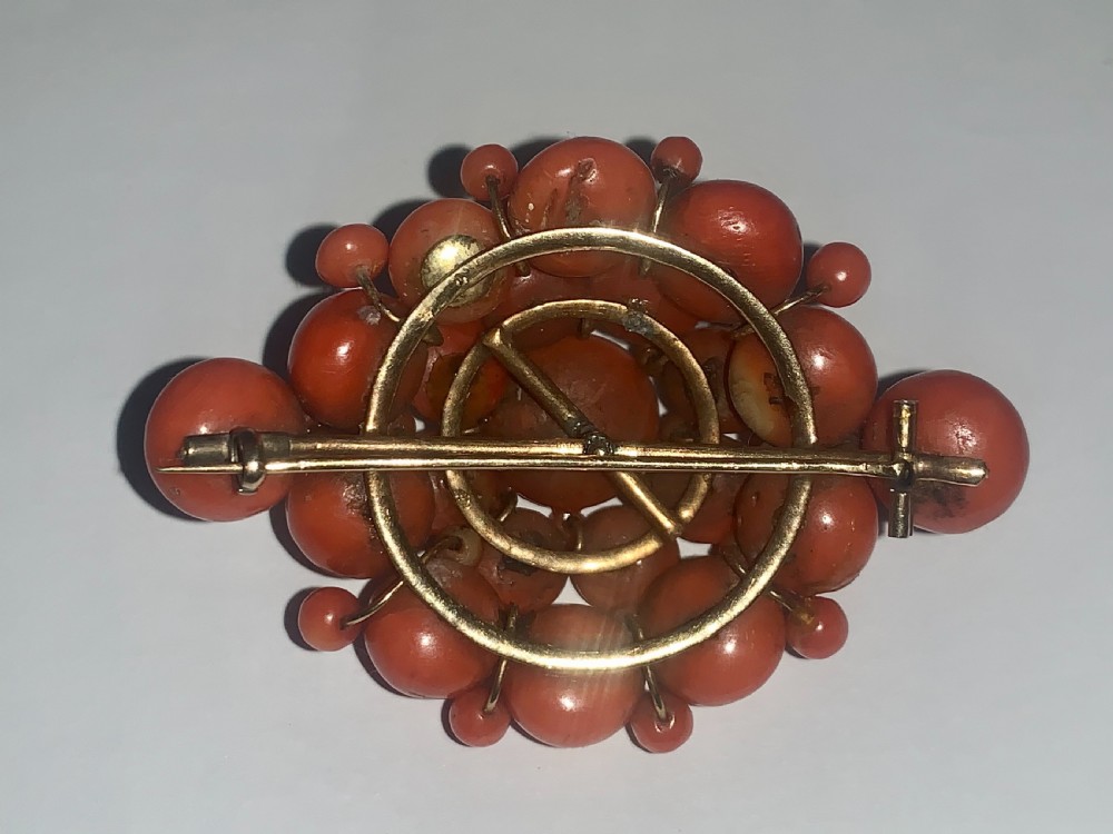 An antique Victorian domed cluster brooch composed of polished salmon-pink coral beads set in a multi-tiered arrangement. View V
