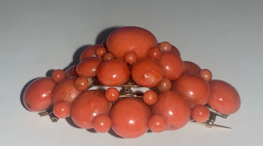 An antique Victorian domed cluster brooch composed of polished salmon-pink coral beads set in a multi-tiered arrangement. View VI