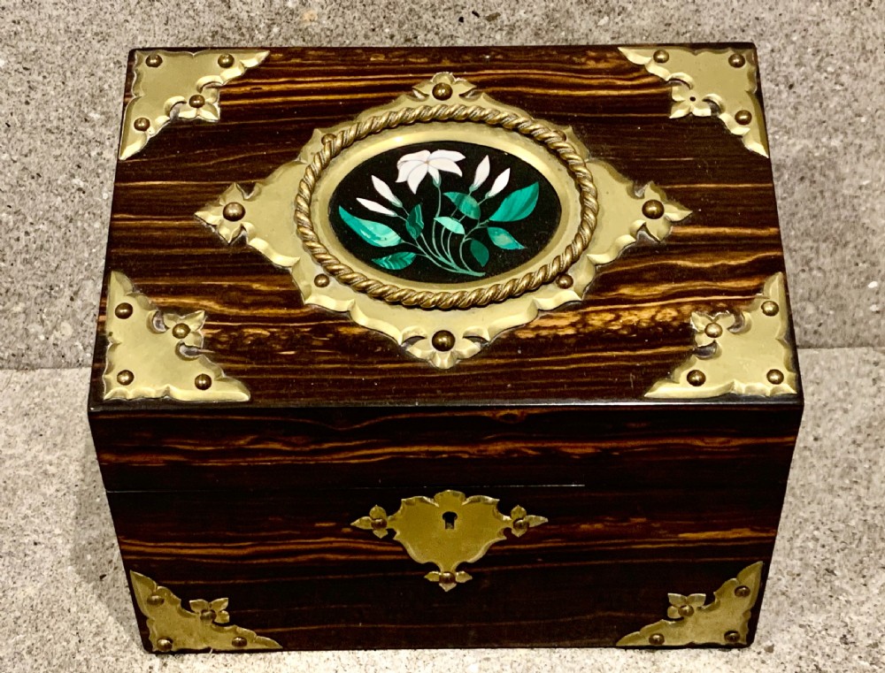 A dark striped coromandel wood stationery box with brass corner mounts, a central oval pietra dura floral plaque, and a brass keyhole escutcheon. View V