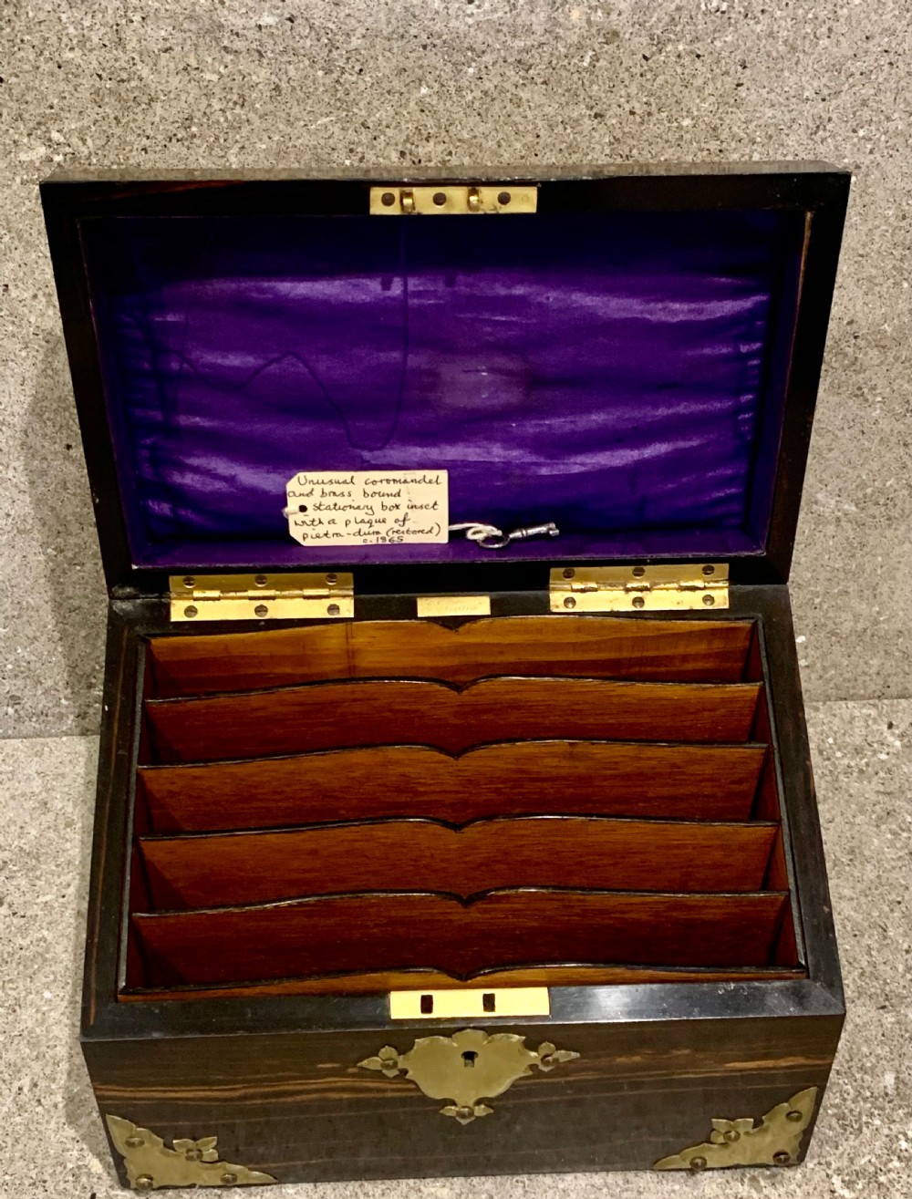 A dark striped coromandel wood stationery box with brass corner mounts, a central oval pietra dura floral plaque, and a brass keyhole escutcheon. View IX